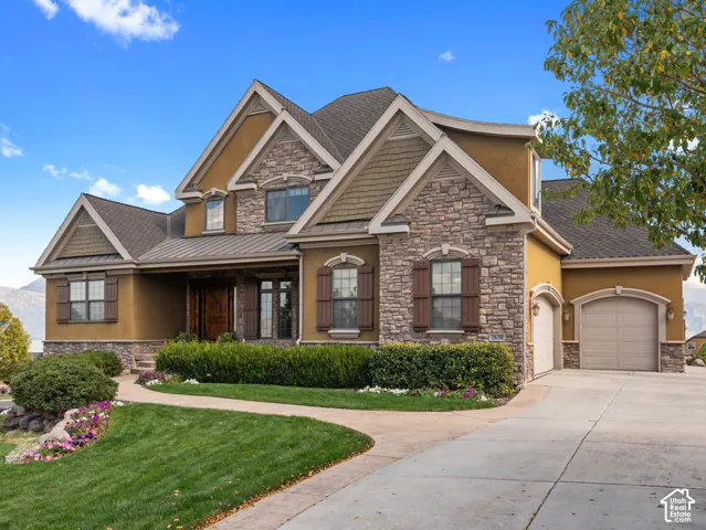 Multi-gabled exterior featuring stone veneer, stucco siding, and shake-shingle accents with an attached three-car garage