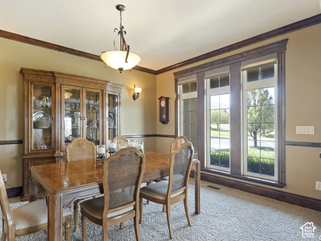 Dining space featuring rich wood crown molding and chair rail, built-in floor-to-ceiling cabinetry, multi-pane windows with wood trim, and a multi-arm overhead light fixture