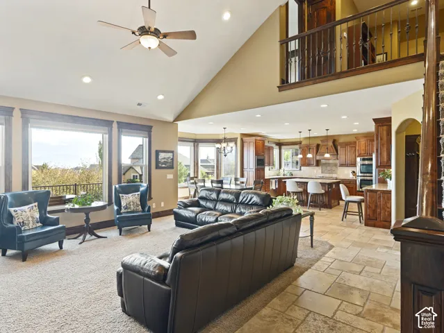 Open-concept floor plan featuring a vaulted ceiling, large picture windows, tile flooring, custom wood cabinetry, and a mezzanine with metal railing
