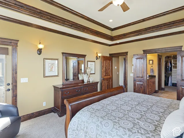 Tray ceiling with stained wood trim, wall-mounted light fixtures, solid wood interior doors, and built-in walk-in closet shelving