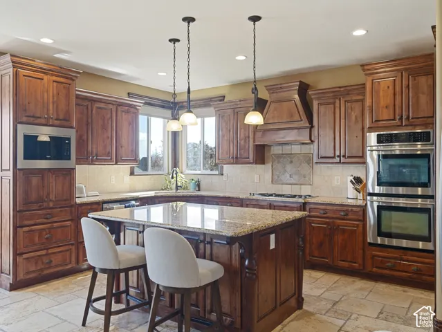 Kitchen featuring stained cabinetry, stone countertops, integrated stainless steel double wall ovens, built-in microwave, and stone-tile flooring