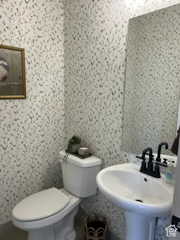 Powder room featuring floral wallpaper, a white pedestal sink, and matte black plumbing fixtures