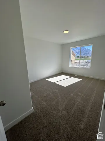Neutral-toned carpeted room featuring a single-pane window with mountain scenery