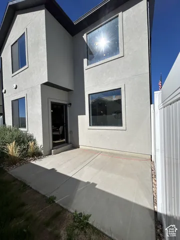 Stucco exterior featuring a concrete patio, large windows, and a privacy fence