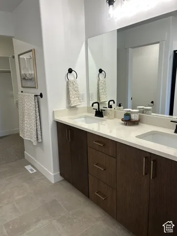 Double-vanity with stone-composite countertop, undermount sinks, dark wood-finish cabinetry, matte black hardware, and large wall-mounted mirror