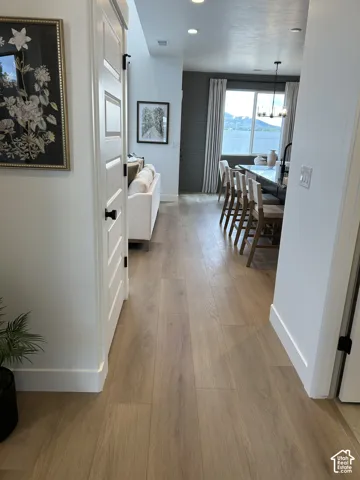 Wood-finish flooring throughout, horizontal plank wall accent, recessed lighting, and kitchen island featuring a stone-composite countertop