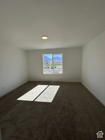 Neutral-toned wall-to-wall carpeting, expansive window with mountain backdrop, and flush-mount ceiling lighting