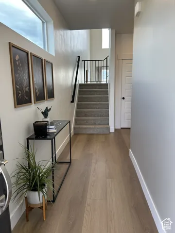 Interior entry featuring wood-finish flooring, staircase with a black metal railing, transom window, and a multi-panel door