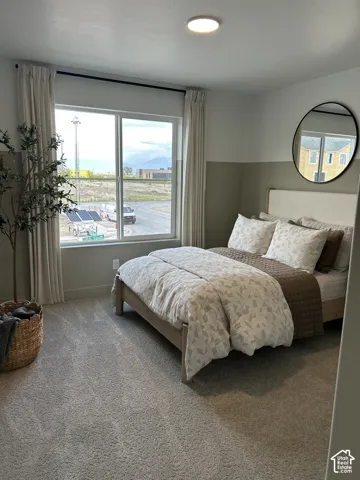 Neutral-toned room featuring high-pile wall-to-wall carpeting, two-tone wall paint, a large picture window, and a circular wall-mounted mirror with a black frame