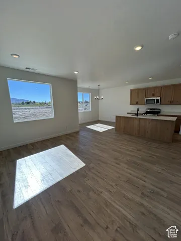 Open-concept interior featuring wood-finish flooring, recessed lighting, a center island with a stone-surfaced countertop, and natural wood cabinetry