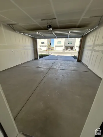 Attached two-car garage featuring a smooth concrete floor, finished drywall, and an overhead automatic door opener