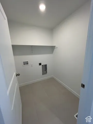 Dedicated utility room featuring neutral ceramic tile flooring, overhead recessed lighting, and a built-in shelving unit