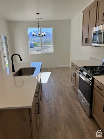 Kitchen featuring an island with a quartz countertop, wood-finish cabinetry, stainless steel gas range, matte black plumbing fixtures, and mountain scenery