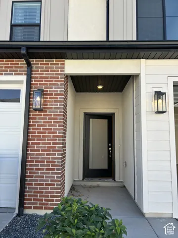 Modern exterior featuring a brick facade, horizontal lap siding, a recessed entry, a glass-panel entry door, and black metal sconce lighting