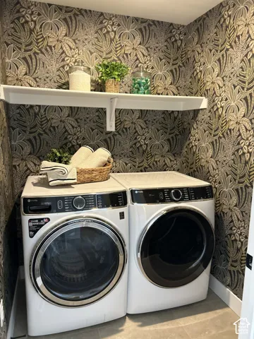 Laundry area featuring patterned wallpaper and a built-in wall-mounted shelf