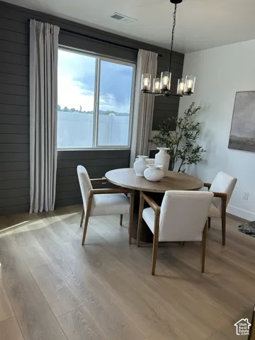 Interior space featuring dark horizontal plank accent wall detailing, large slider window, wood-finish flooring, and a multi-arm metal chandelier with glass shades