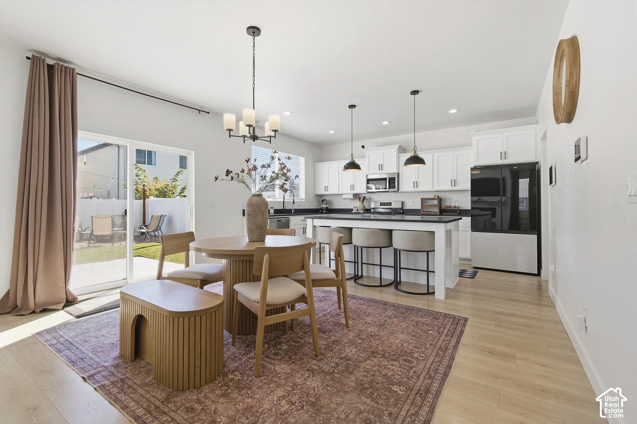 Kitchen featuring white cabinetry, an island with seating, dark countertops, wood-finish flooring, and sliding glass door access to the exterior