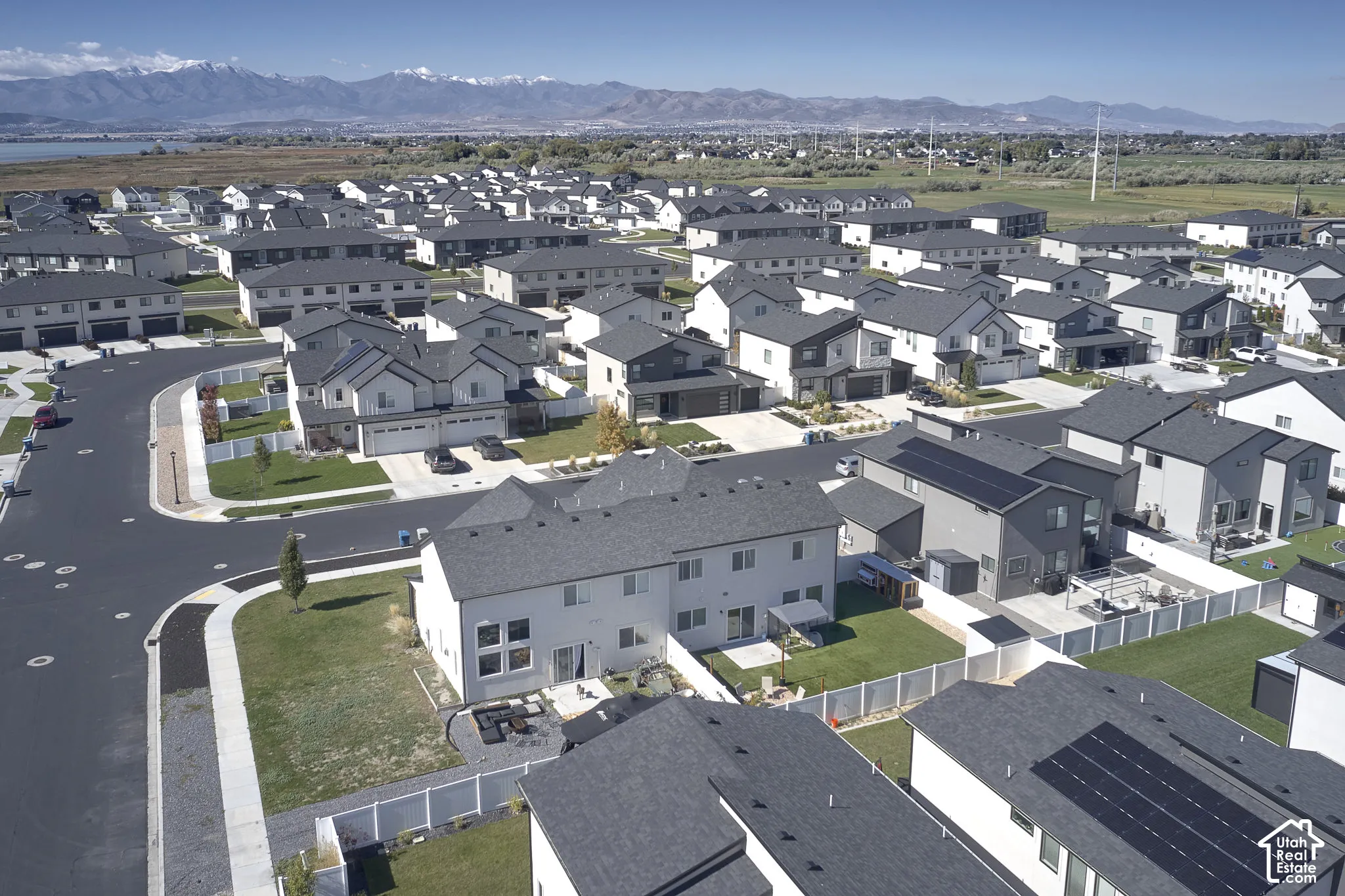 Aerial perspective featuring residential lots, fenced backyards, paved streets, and a prominent mountain range backdrop