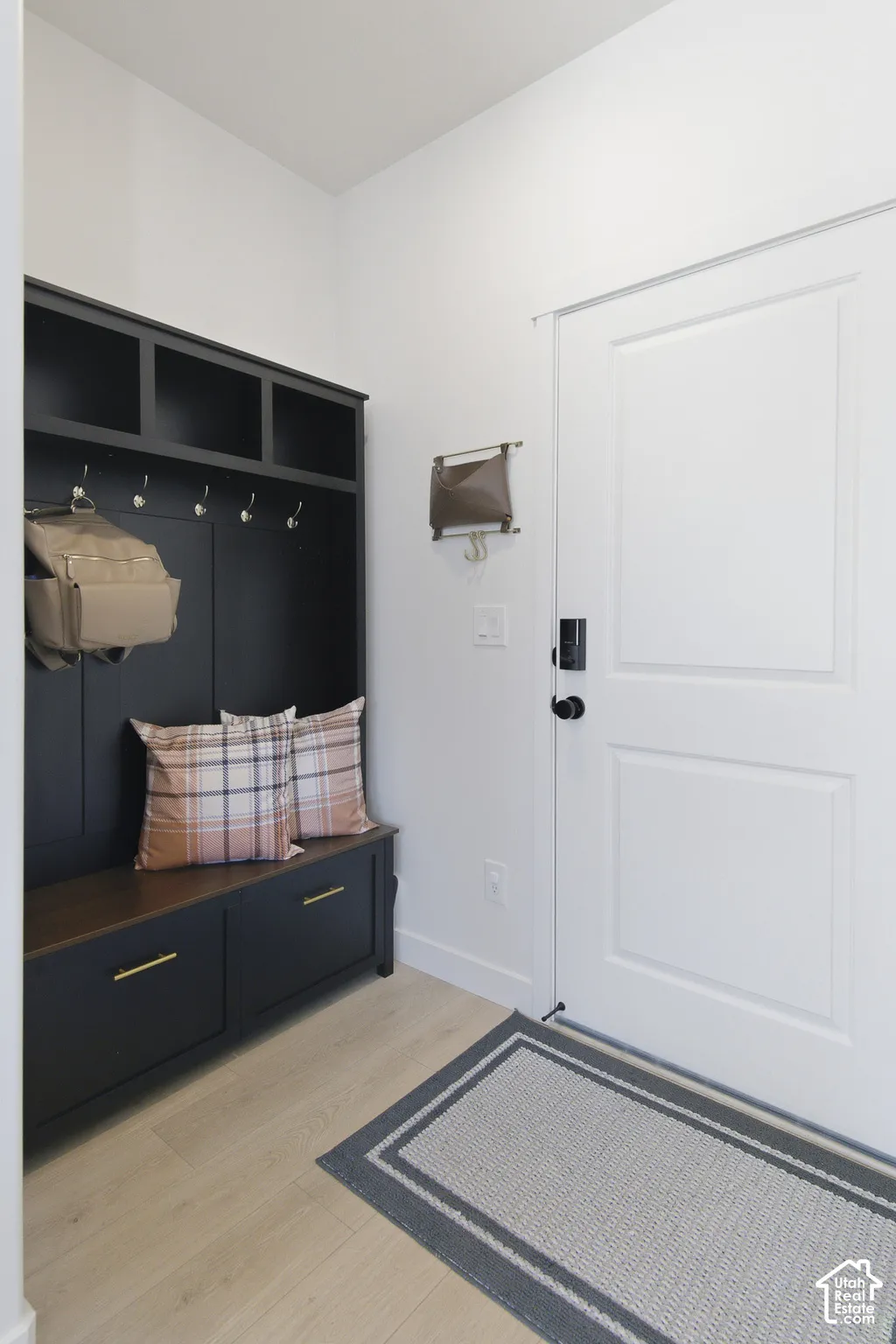 Built-in mudroom cabinetry featuring a dark finish, integrated storage cubbies, brushed brass hardware, and a wood-surface bench