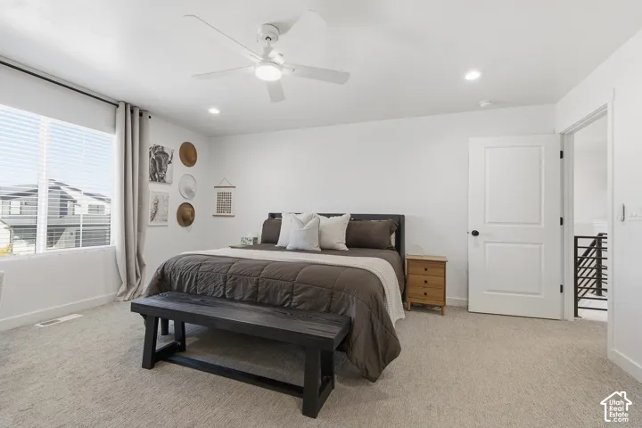 Neutral carpeting, crisp white walls, recessed lighting, and a white ceiling fan with integrated light