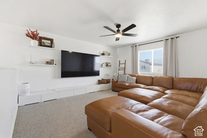 Wall-mounted floating shelving, built-in low-profile storage cabinetry, carpeted flooring, and ceiling-mounted fan with integrated lighting