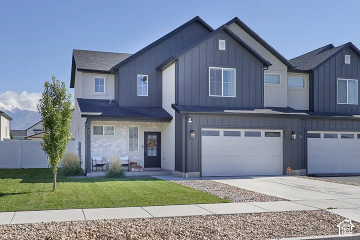 Two-story exterior featuring vertical siding, stone veneer accents, an attached two-car garage, and a concrete driveway