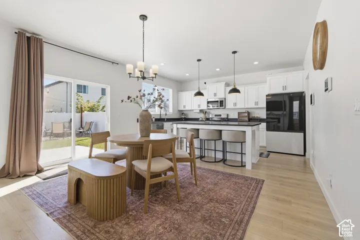 Kitchen featuring white cabinetry, an island with seating, dark countertops, wood-finish flooring, and sliding glass door access to the exterior