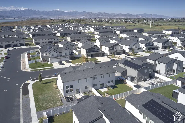 Aerial perspective featuring residential lots, fenced backyards, paved streets, and a prominent mountain range backdrop