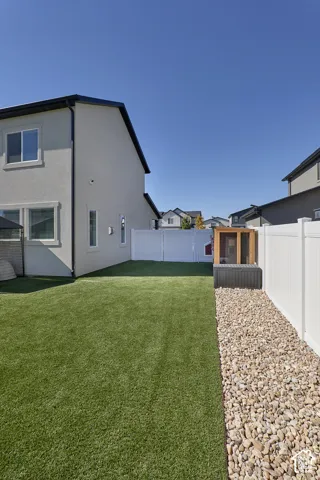 Low-maintenance backyard featuring synthetic turf, stone landscape edging, and a full-height white vinyl privacy fence