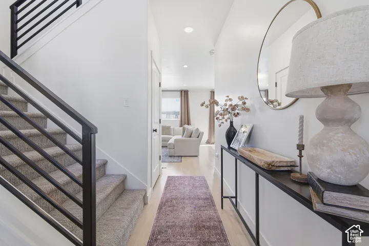 Foyer featuring wood-finish flooring, recessed lighting, and a staircase with a minimalist matte black metal railing