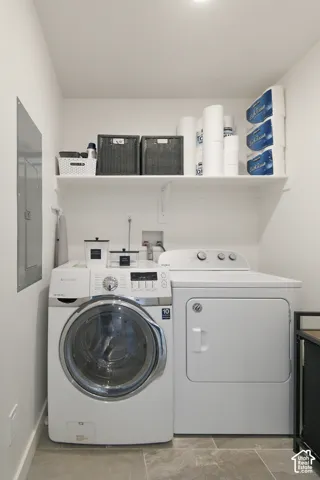 Laundry area featuring neutral tile flooring, white walls, and a built-in overhead storage shelf