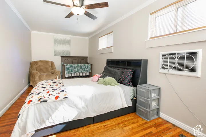 Wood-finish flooring, ceiling fan with integrated lighting, and wall-mounted air conditioning unit