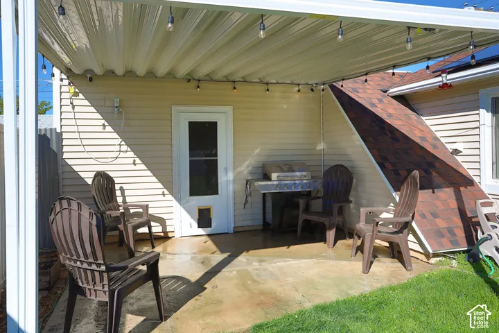 Covered concrete patio featuring horizontal vinyl siding, a metal overhead structure, and an exterior door with integrated pet access