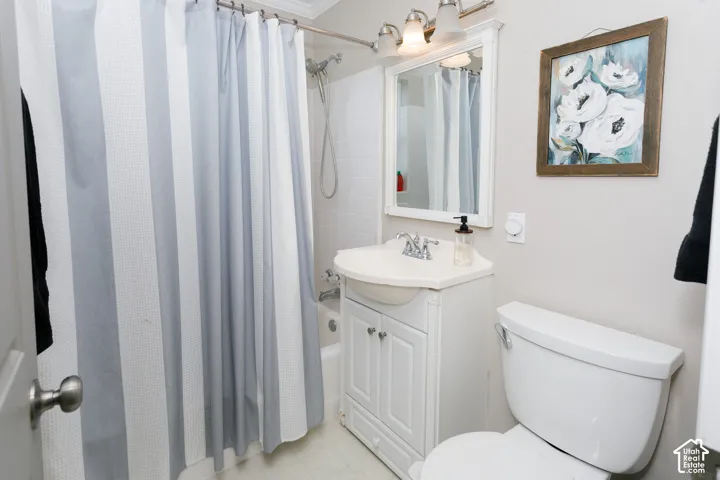 White vanity with an integrated basin, framed wall-mounted mirror, three-light fixture with glass shades, and a shower-tub combination featuring a handheld sprayer