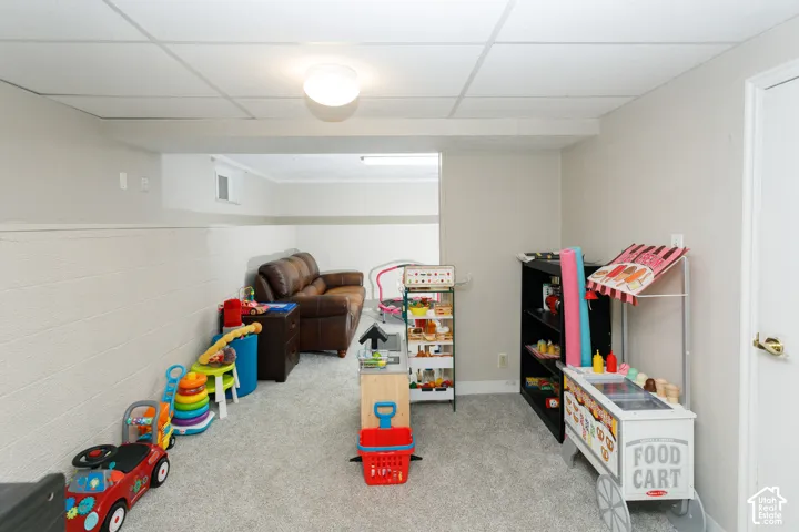 Interior space featuring neutral wall-to-wall carpeting, painted masonry walls, a suspended ceiling, and recessed ceiling lighting