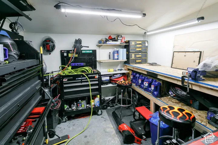 Workspace featuring integrated linear overhead lighting, tiered open shelving, and a built-in workbench with a particle board surface