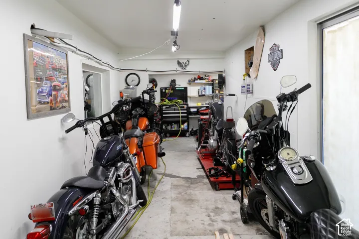 Garage space featuring concrete flooring, built-in recessed wall shelving, and linear ceiling-mounted lighting