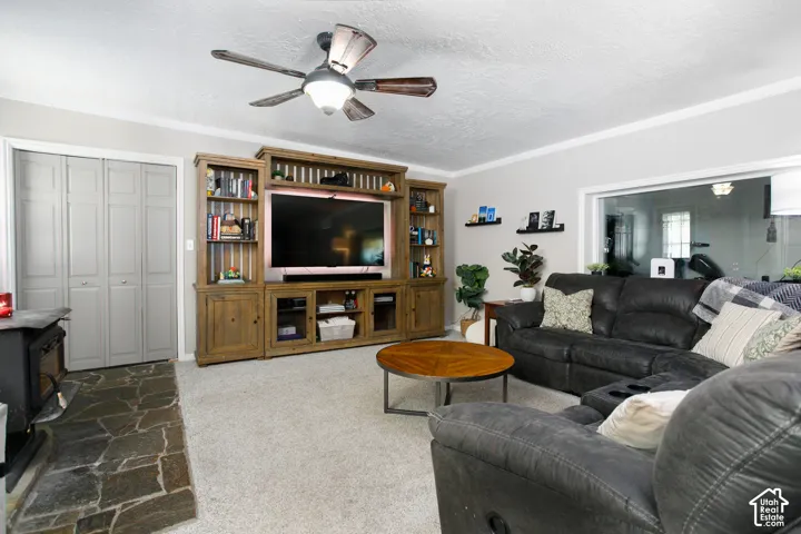 Custom built-in wood cabinetry, natural stone hearth, wood-burning stove, ceiling fan with light fixture, and bi-fold closet doors