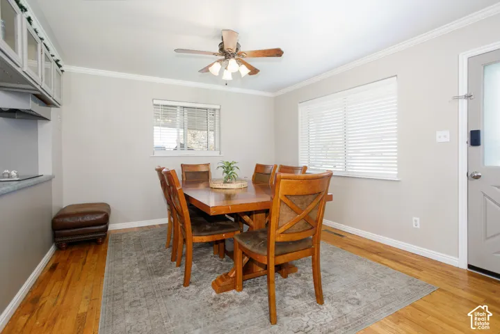 Dining area featuring wood-finish flooring, built-in cabinetry, a multi-light ceiling fan, and horizontal window blinds