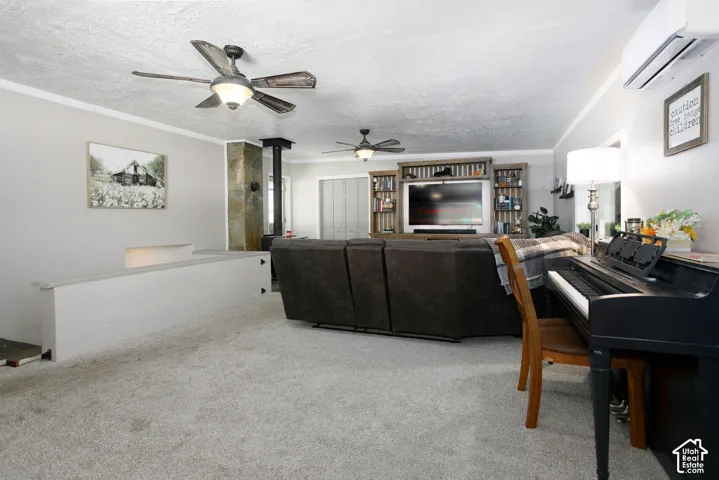 Living area featuring two ceiling fans, a stone-accented wood stove, a built-in entertainment center, and a wall-mounted mini-split HVAC unit