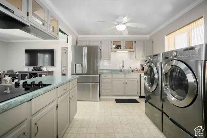 Multipurpose utility space featuring stainless steel appliances, solid-surface countertops, custom cabinetry with glass-front display doors, and a ceiling-mounted light fixture