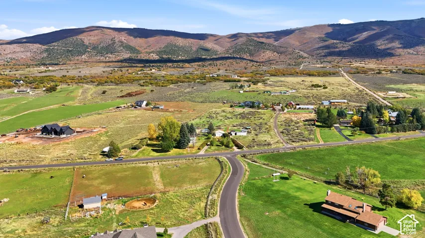 Aerial perspective showcasing expansive acreage, paved road access, and mountain range backdrop