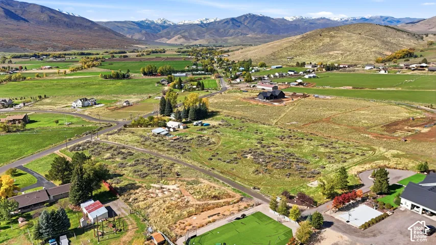 Aerial perspective featuring expansive acreage, open terrain, paved access roads, and snow-capped mountain backdrop