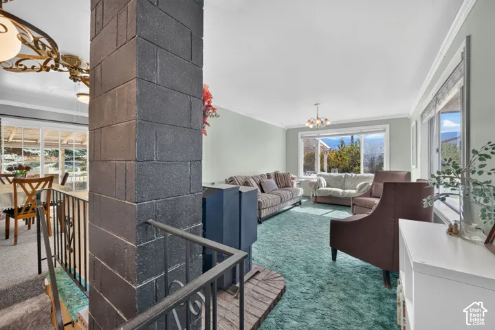Exposed cinder block support column featuring a freestanding metal stove on a brick hearth, large picture windows, and metal railing