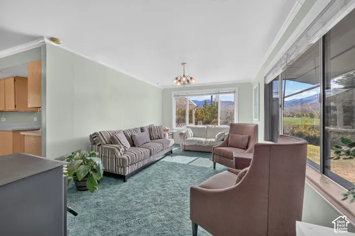 Living area featuring crown molding, large windows with mountain scenery, and a multi-arm chandelier
