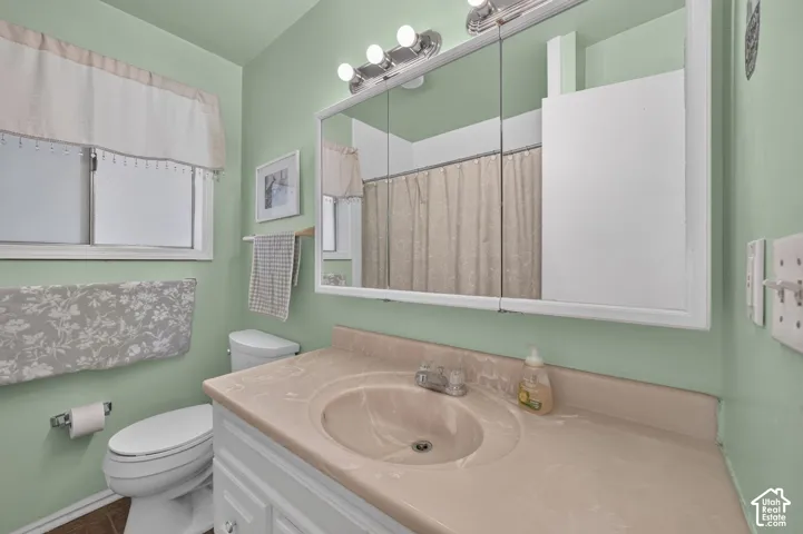 Bathroom featuring a tri-fold medicine cabinet, vanity with a molded countertop and integrated sink, four-light fixture, and sliding window