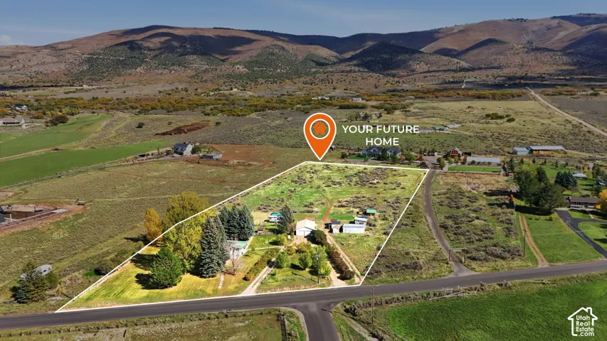 Expansive parcel of land featuring mature trees, a detached workshop, and prominent mountain backdrops