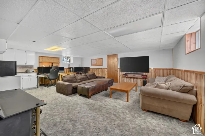 Multi-purpose interior space featuring white cabinetry, wood-paneled wainscoting, a suspended ceiling, and recessed lighting
