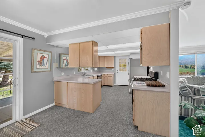 Kitchen featuring light-finish wood cabinetry, solid-surface countertops, recessed lighting, and a sliding glass door