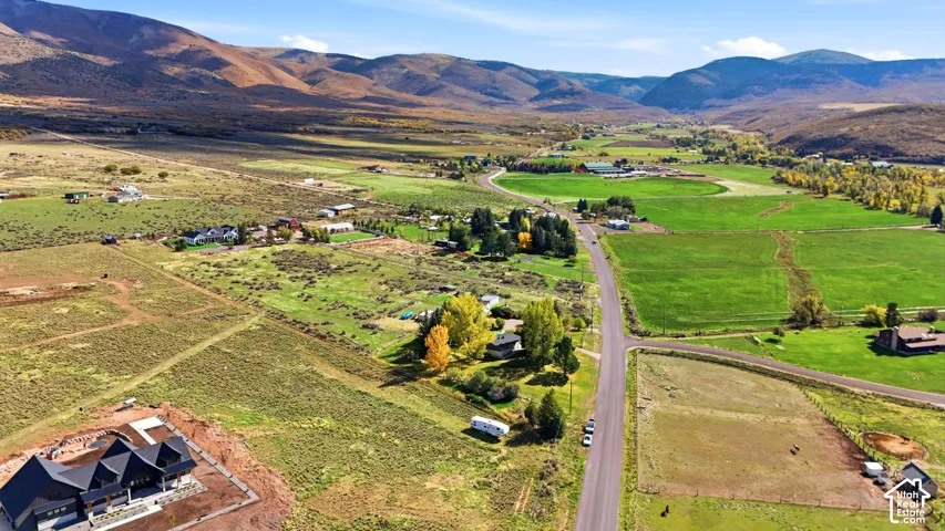 Aerial perspective featuring expansive mountain terrain, open valley meadows, and mature foliage